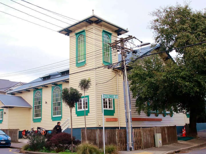 Two-storey timber church building painted cream and teal with corner tower