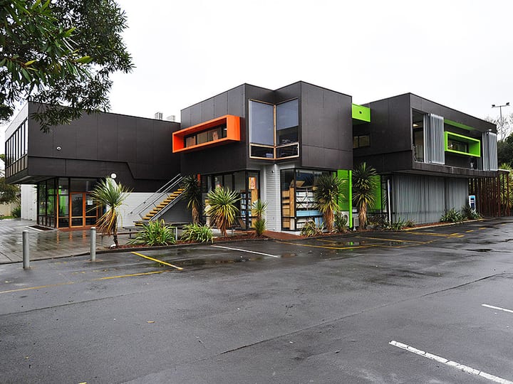 Contemporary dark-cladded two-storey building with bold orange and green accents