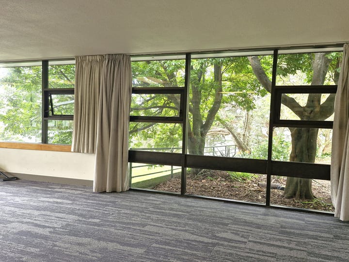 Empty carpeted room with floor-to-ceiling windows overlooking trees