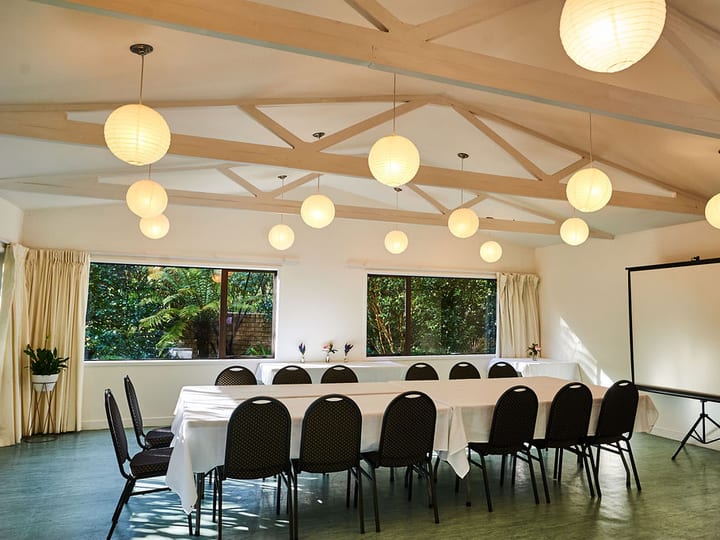 Bright meeting room with vaulted timber ceiling, globe pendant lights, long table and projection screen