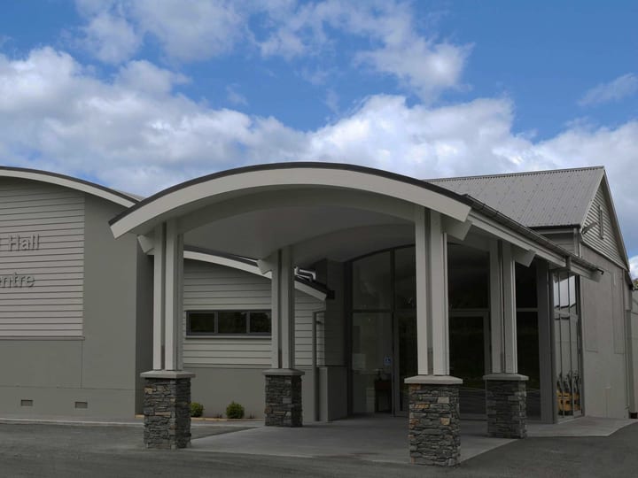 Contemporary curved-roof community hall with stone-clad entrance columns and signage