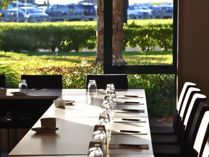 Conference room with boardroom table set for a meeting, garden views through windows