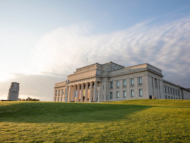 Classical stone museum building on open grass field