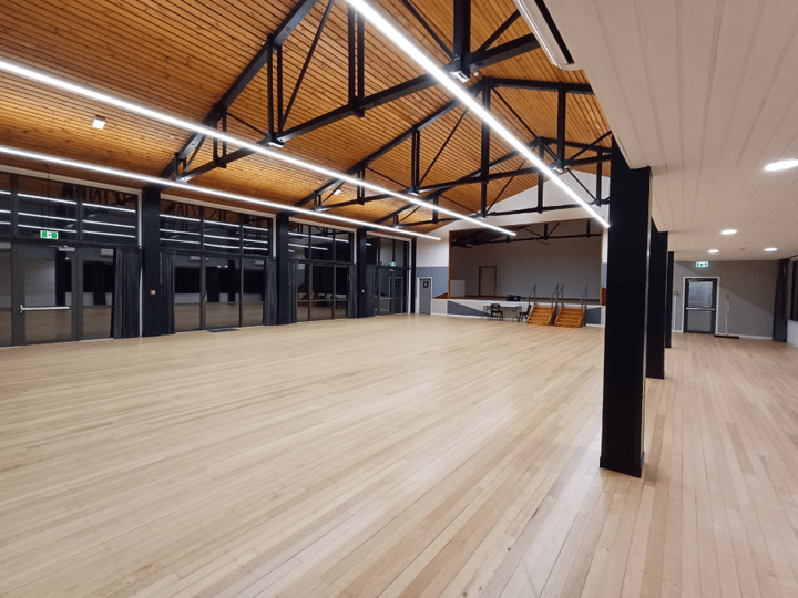 Large open hall with timber and steel roof trusses and wooden floor