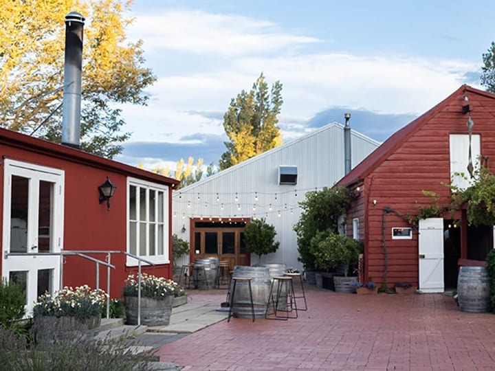 Red painted timber buildings with a courtyard, barrel planters, and autumn trees