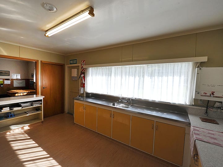 Basic kitchen with orange laminate cabinets, stainless bench, and long window