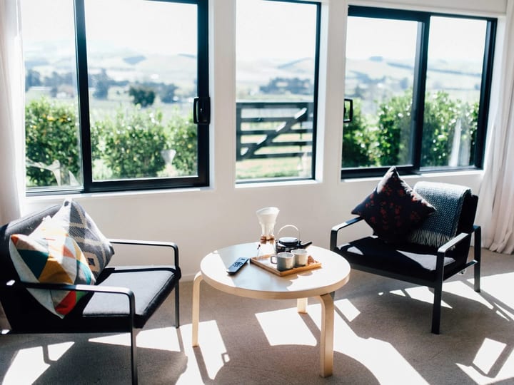 Bright lounge with two armchairs and a round coffee table overlooking vineyard