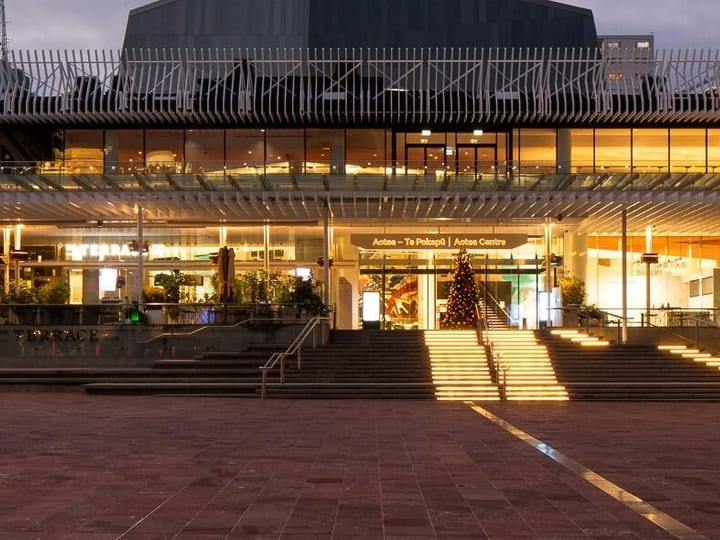 Large civic building exterior at dusk with illuminated entrance and plaza