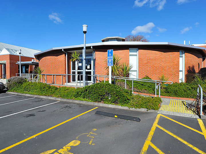 Curved brick library building with car park and blue sky