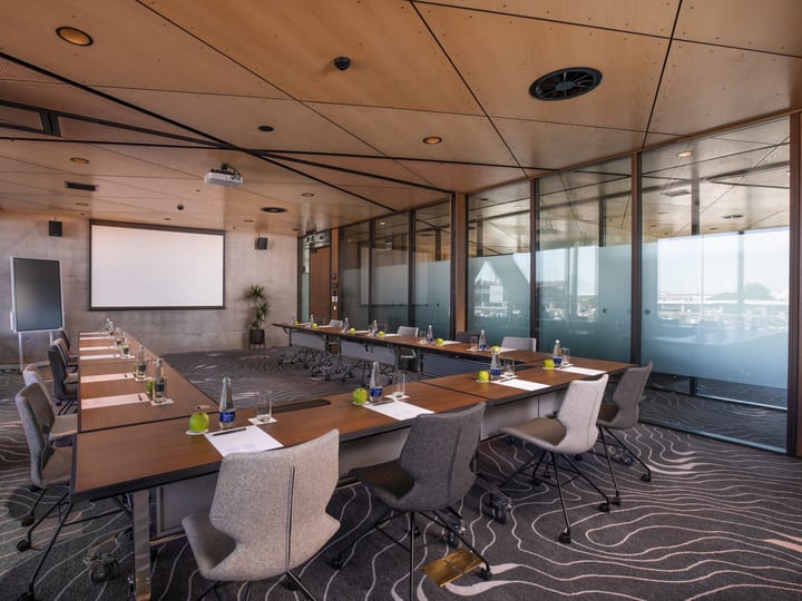 Meeting room with long U-shaped table, projection screen and glass partition walls