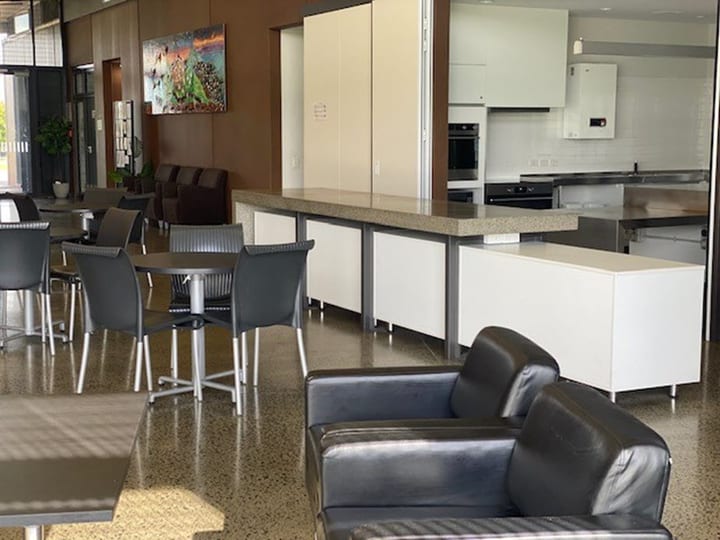 Open-plan function area with kitchen servery, leather sofas, and polished concrete floor
