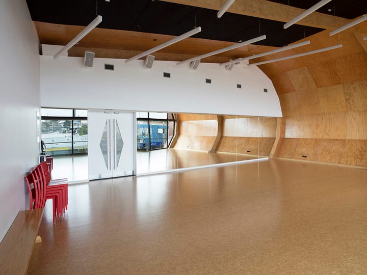 Open studio with cork floor, full-height windows, plain white walls, and timber ceiling panels