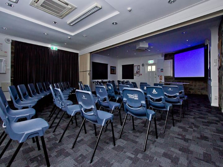 Function room in theatre layout with rows of blue chairs and projection screen
