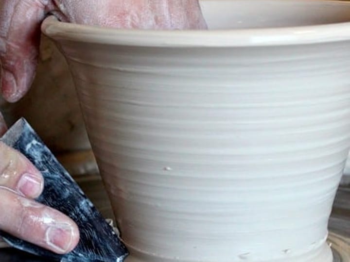 Hands shaping clay on a pottery wheel