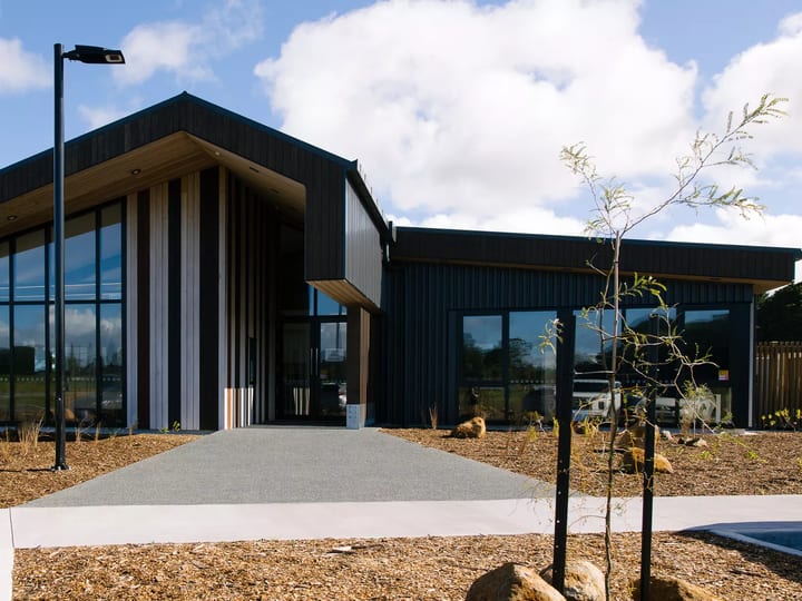 Single-storey dark-clad building with large glazed entry and timber accents