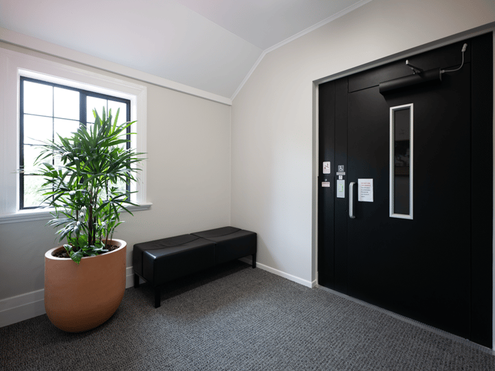 Lobby area with potted plant, bench seat and black double doors