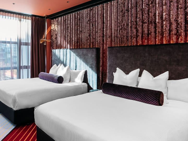 Twin hotel room with matching beds, feature wall and striped carpet