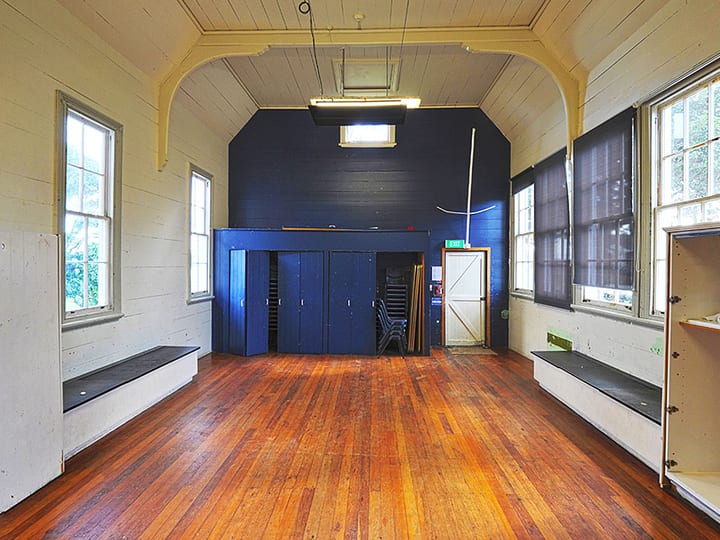 Hall interior with arched timber ceiling, polished timber floor, and raised platform at far end