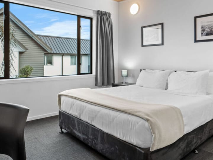 Simply furnished hotel bedroom with timber ceiling and garden view
