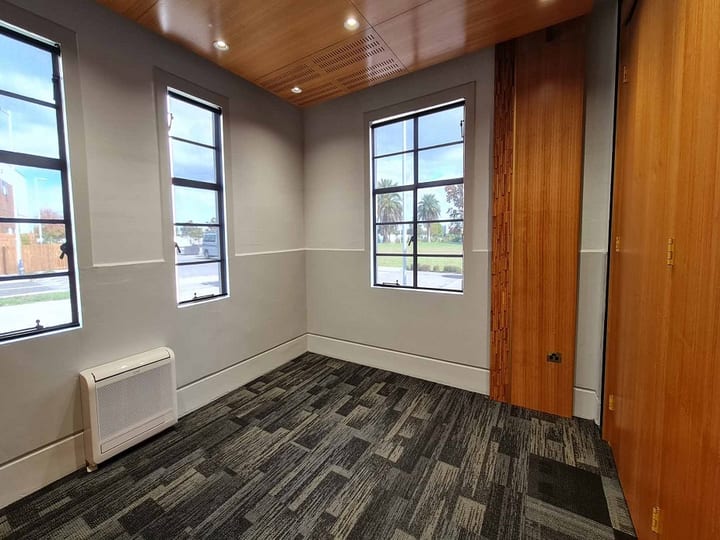 Small meeting room with rectangular table, chairs, and wall-mounted screen