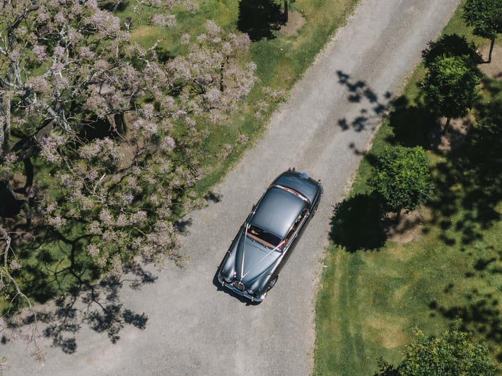 Aerial view of classic car on gravel drive through venue grounds