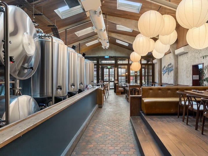 Brewery interior with stainless fermentation tanks, timber ceiling and pendant lights