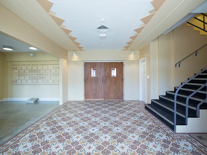 Entry foyer with decorative mosaic tile floor, timber doors, and staircase