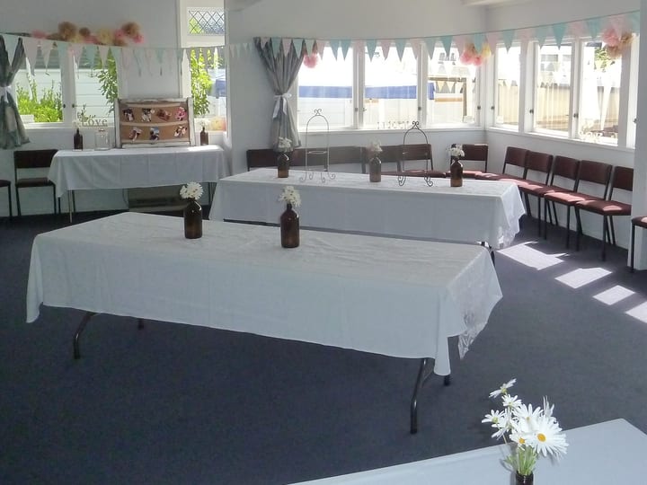 Hall room set up for a function with trestle tables, white cloths, bunting and decorations