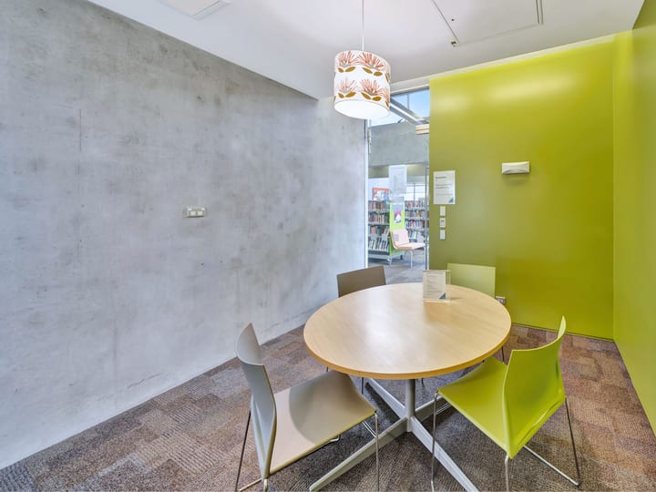 Small meeting room with round table, lime-green accent wall and pendant light