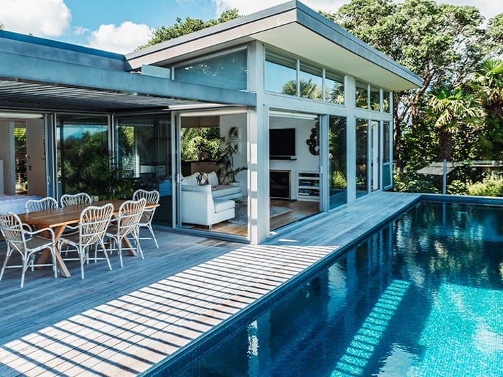 Modern lodge exterior with infinity pool and deck sun loungers