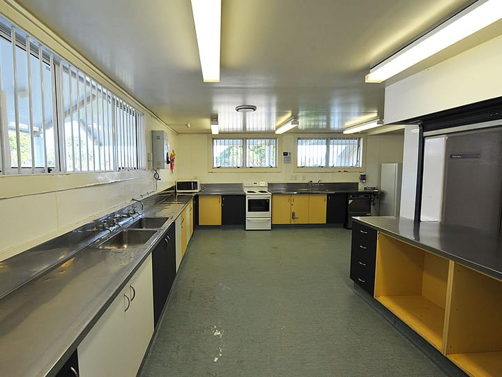 Commercial kitchen with yellow cabinets, stainless benches and large refrigerator