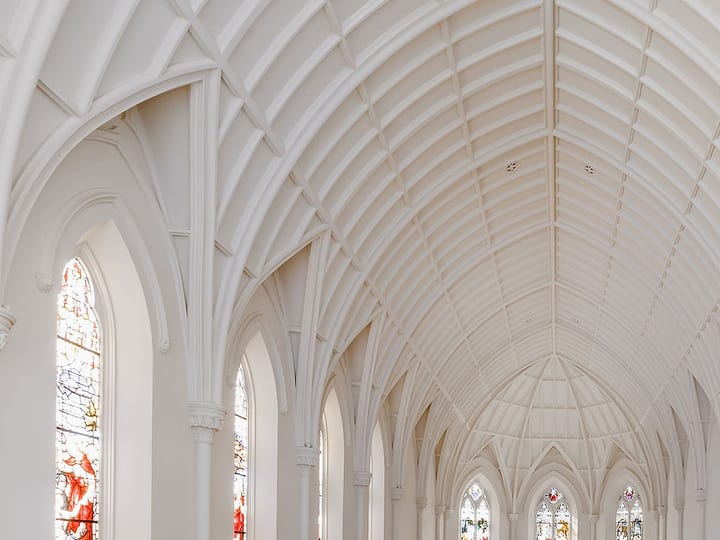 White chapel interior with high vaulted Gothic arches and stained glass windows