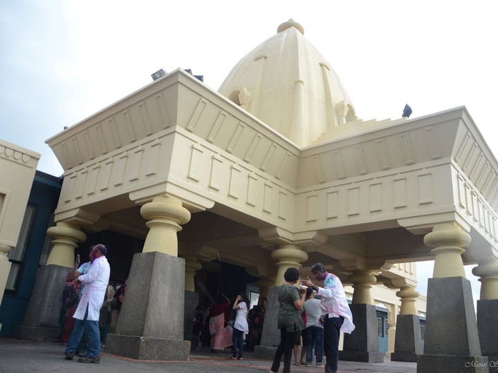 Ornate building entrance with columns and a dome structure, people gathered at the door