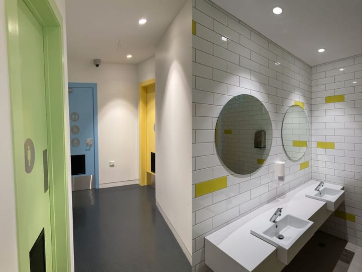 Colourful bathroom corridor with tiled basin vanity and blue and yellow accent doors