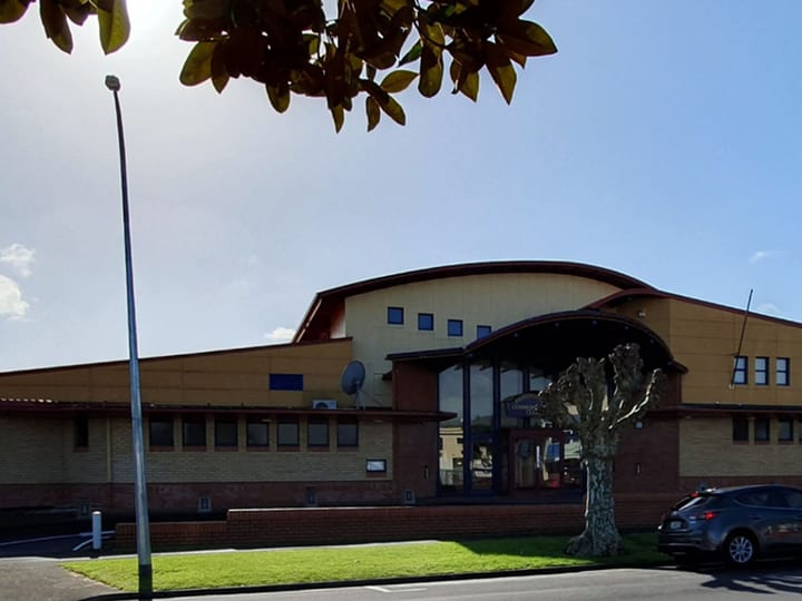 Large club building exterior with curved roof and entrance canopy