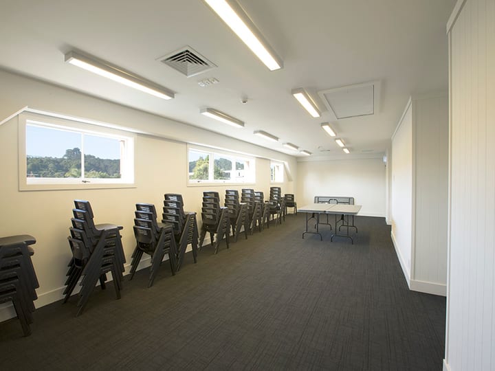 Plain meeting room with stacked chairs along walls and a folding table