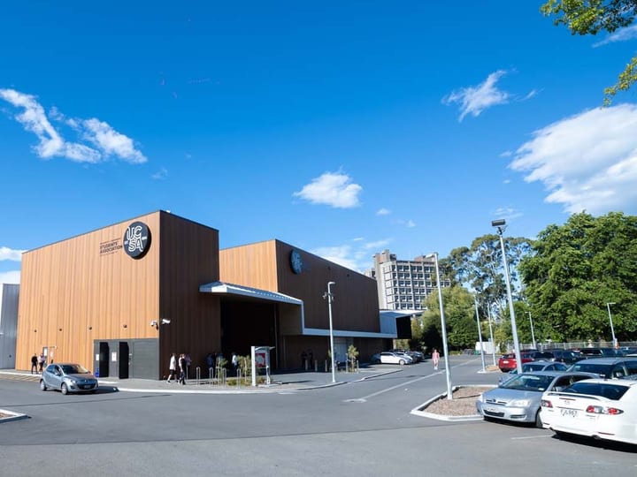 Modern building with timber cladding and large car park under blue sky