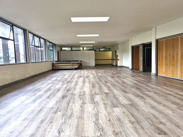 Empty meeting room with timber flooring and windows overlooking street