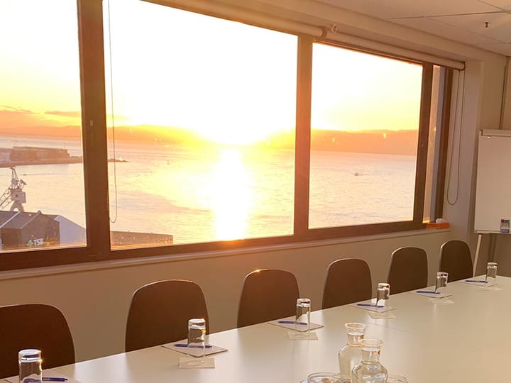 Small meeting room with central table and sunset harbour view