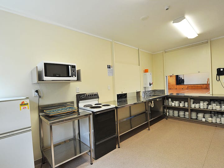 Basic kitchen with stainless benches, stove and storage shelves