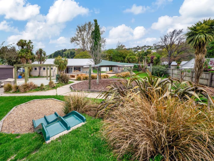 Outdoor grounds with garden beds, trees and small playground equipment