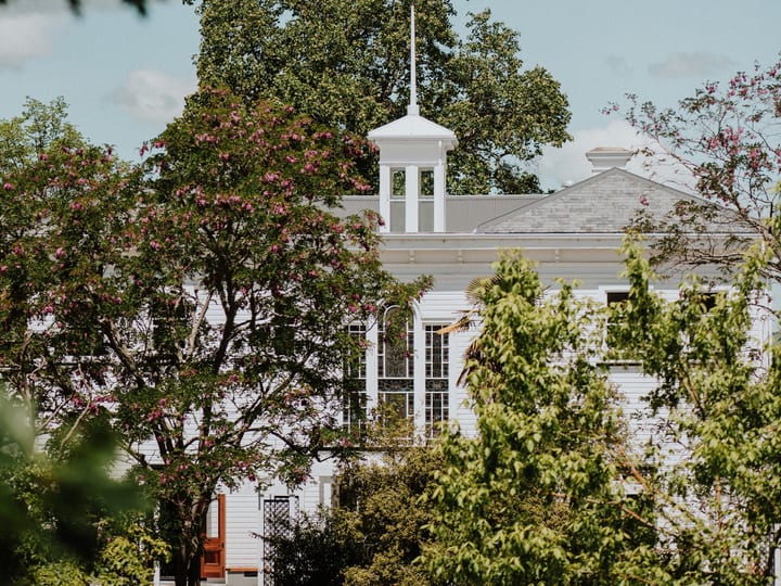 White heritage villa cupola visible through garden trees