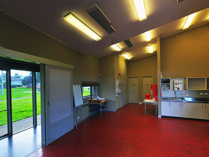 Utility hall with red concrete floor, sliding glass doors to lawn, and small kitchen