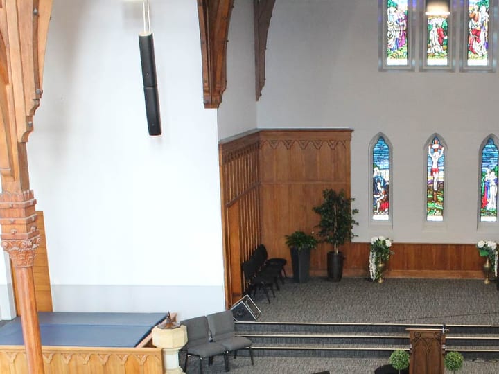Church sanctuary from balcony showing stained glass, organ pipes and raised platform