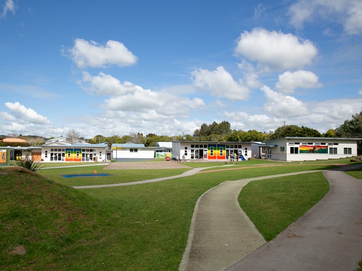 School buildings and playground on open lawn under blue sky