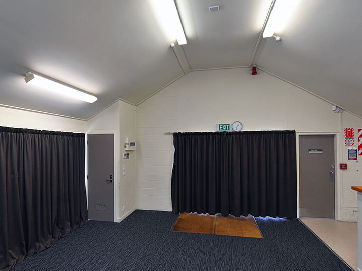 Small hall with pitched ceiling, dark curtains and carpet floor