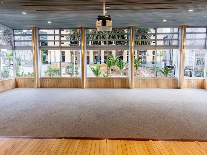 Open function hall with large glazed walls, timber panelling and herringbone carpet