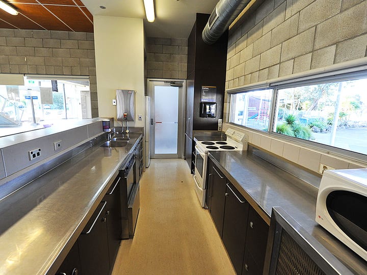 Galley kitchen with stainless steel benches, stove, sink and microwave
