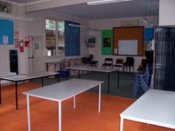 Plain community room with tables, chairs and fluorescent lighting