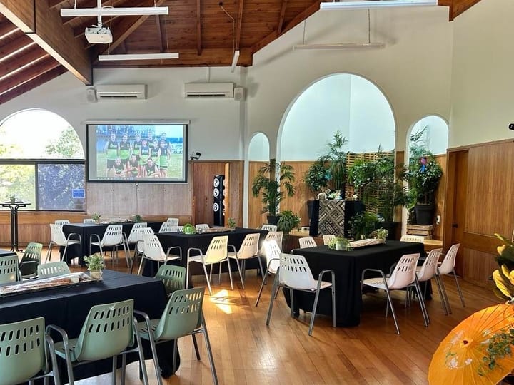 Hall with timber vaulted ceiling, arched windows, tables set with black cloths